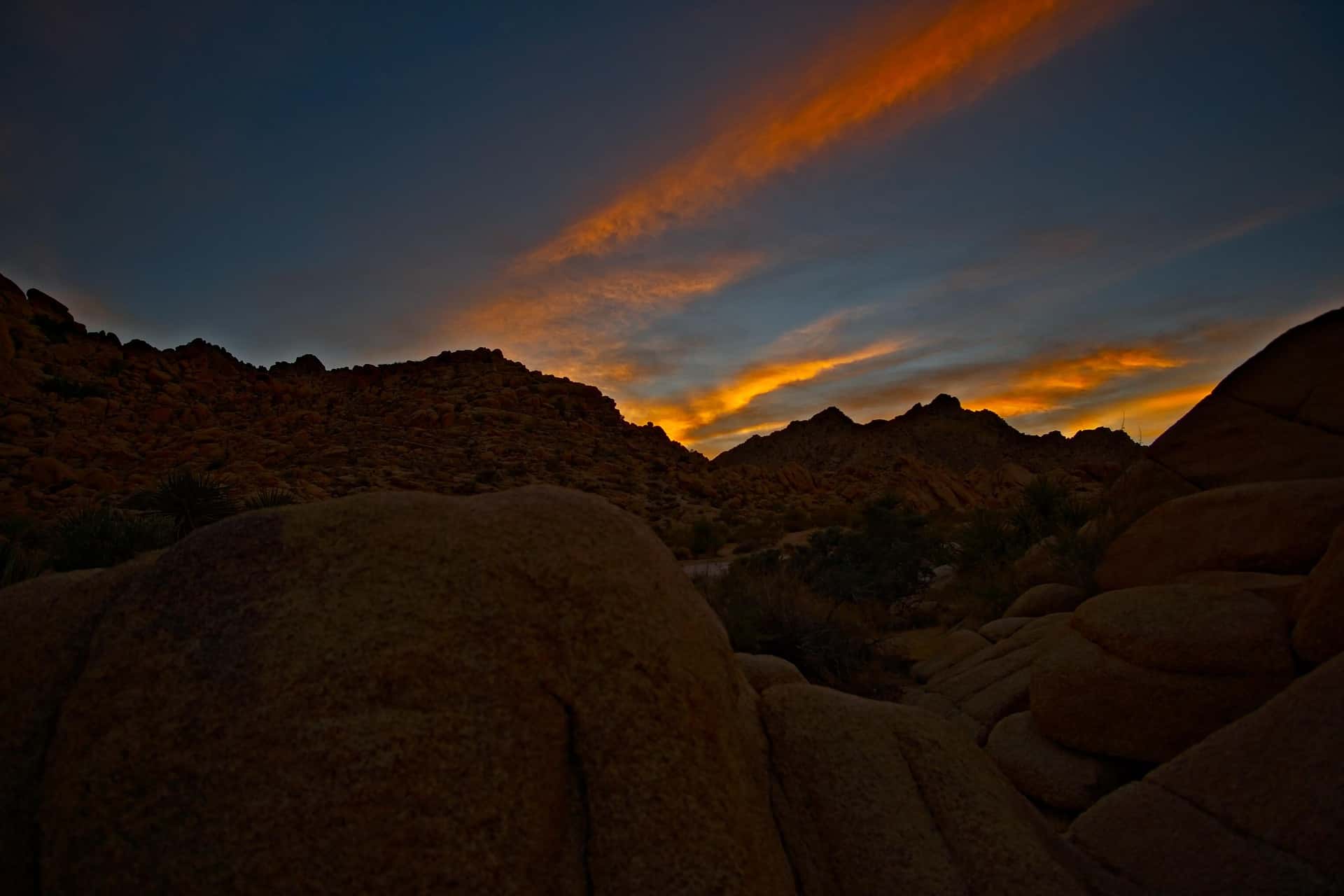 Granite boulders in the Joshua Tree desert beneath a burning sunset sky